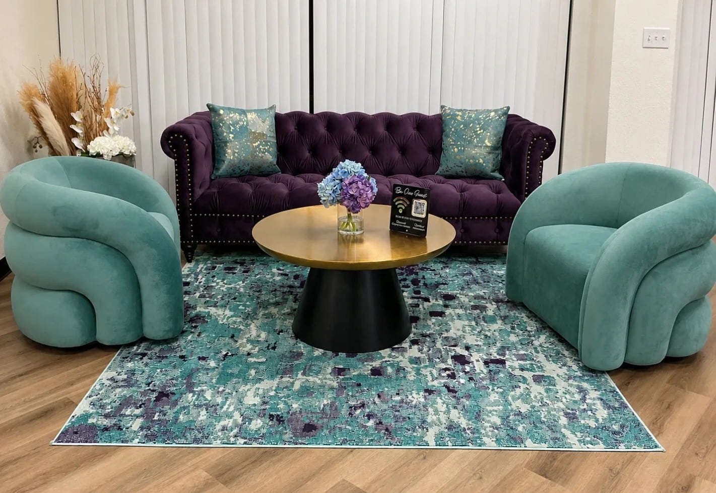 Client lounge with teal chairs and a purple sofa at Crystal Luxe Salon Suites in DeSoto, TX